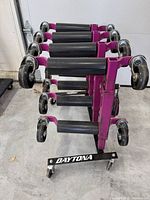 Front view of black Daytona storage rack holding four purple GoJak wheel dollies
