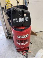 Red vertical tank electric air compressor showing brand, horsepower, tank capacity, and PSI rating