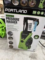Original box of Portland electric pressure washer showing brand, pressure rating (1750 PSI), flow rate (1.3 GPM), and features.