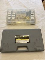 Closed gray plastic case of Pittsburgh 60pc Tap and Die Set next to clear plastic organizer bin with dividers containing screws and fasteners