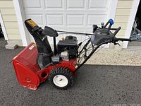 Side profile showing red housing, steel auger intake and large treaded wheel