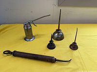 Wide view of all items on yellow cloth showing four oil cans and grease tool