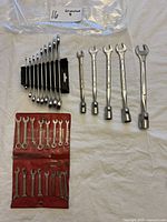 Photo of assorted wrenches including combination wrenches, socket wrenches, and small wrenches in pouch.