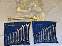 SAE and metric combination wrench sets in blue roll-up plastic cases alongside a separate Craftsman wrench.