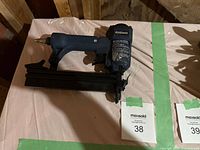 Full side view of the Mastercraft pneumatic brad nailer showing blue body, black nail magazine, and pneumatic connector.