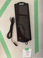 Full view of Coleman solar panel with attached cable coiled next to it, showing its rectangular shape and Coleman branding.