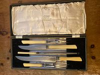 Top view of entire serving set inside case showing knives and forks aligned in black velvet base and stained satin lid lining with Cutlass branding