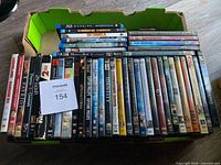 Box with assorted DVD cases showing multiple movie titles and TV series