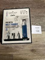 Front view of sealed box showing Conair Pro Metal Multi Trimmer with 4 magnetic attachments and stand, branding and product name.