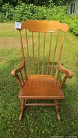 Front and side view of the wooden rocking chair showing the curved backrest with vertical spindles and armrests.