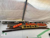 Several metal and plastic levels, wooden ruler and metal stakes on a flat surface. Items are rusted and dirty.