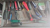 Photo showing various screwdrivers in a drawer with mixed handle colors and types, clearly showing assortment and condition