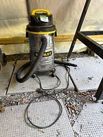 Front and side view of Stanley wet/dry vacuum with hose and power cord visible on concrete tile floor.
