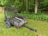 Side view of trailer showing mesh sides, frame, ramp in upright position and hitch wiring