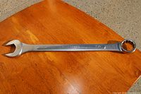 Photo of a silver 1-1/8 inch Truecraft combination wrench on a wooden surface, showing open-end and box-end sides and the markings on the handle.