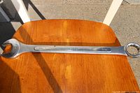 Photo of a single combination wrench with 1-5/16 inch size marking on wooden surface.