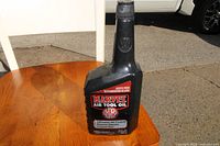 Photo of Marvel Air Tool Oil black plastic bottle with red and white label on wooden surface.