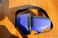 Photo of blue and black E-A-R brand earmuffs showing ear cups and adjustable headband on wood surface.