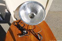 Top-down view showing the lamp's reflective bowl shade, electrical cord with plug, and clamp support.