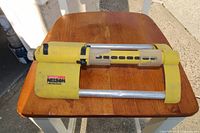 Yellow Nelson oscillating lawn sprinkler viewed from the side on a wooden table outdoors showing label and sprinkler arm