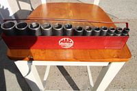 Front view of the 13 deep impact sockets ranging in size, displayed in a red metal rack with MAC Tools logo.