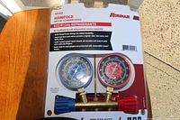 Front packaging showing the Robinair manifold gauge set with two gauges and labeling about use with R22/R134a refrigerants.