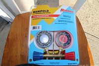 Photo of unopened packaging showing Robinair brand manifold gauge set with hoses, clearly marked as for R134a refrigerant.