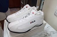 White Fila sneakers placed on Fila shoe box showing side logo, laces and sole detail
