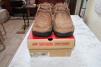 Front view of the brown Skechers Comfort Walkers shoes on top of the original Skechers shoe box, showing overall condition and style.