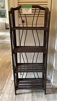 Front view of folding wooden shelf with four slatted shelves and curved top frame with metal decorative back supports