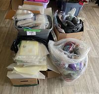 Bins and boxes containing assorted craft supplies including yarn, patterns, and plastic canvas sheets