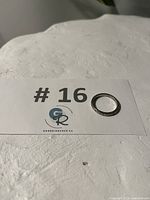 Ring placed next to lot number card '#16' on textured white surface