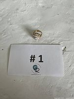 Ring placed on white textured surface with #1 GR card