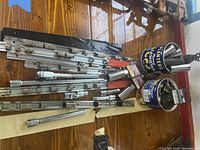 Photo showing spread of ratchet, various extension bars, and metal socket storage bars on wood surface.