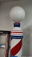 Upper section of the barber pole showing the white globe designed for illumination and red and blue stripes.