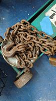 Heavy-duty rusty steel chain hoist with hook.
