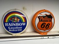 Front view of Rainbow Gasoline Motor Oil and Phillips 66 gas pump globe toppers showing branding and design details.