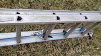 Close-up photo of the aluminum Werner extendable ladder sections showing the rungs, side rails, and blue rope mechanism.