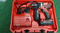 Red hard plastic case open showing Milwaukee drill, battery and charger