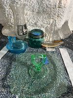 Full view of all five glass items: vase, mason jar, sailboat, blue hen trinket holder, green glass dish