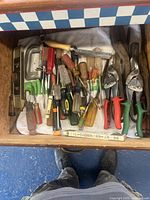 Drawer filled with multiple hand tools including screwdrivers, snippers, level, and mini saw.