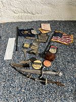 Overview of all items included with various pins, badges, knives, patches spread on carpet