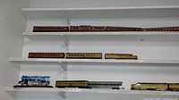Photo showing Southern Pacific Daylight passenger cars and additional train cars on white shelving