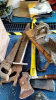 Photo showing vintage wooden miter box, metal saw, Craftsman yellow handled axe, crowbar, scraper, and hatchet tools