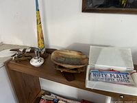 Overview image showing many items on wooden shelves including the woodpecker dispenser, boomerang, ashtrays, lighter, and Nifty Plates.