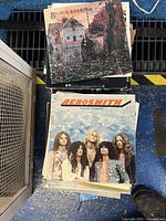 Stack of 12 inch vinyl record albums showing Black Sabbath and Aerosmith covers