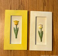 Front view of two rectangular flower wall hangings showing raised tulip flowers in yellow and white frames.