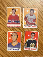 Front view of four 1970-71 O-Pee-Chee hockey cards featuring Marc Tardif (Montreal Canadiens), Alex Delvecchio (Detroit Red Wings), Ross Lonsberry (LA Kings), and Don Marcotte (Boston Bruins).
