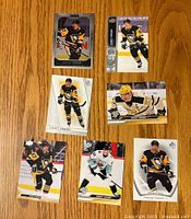 Top side of 7 Sidney Crosby hockey trading cards laid out on a wooden surface showing front images of the player in various poses and uniform styles.