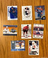 Front view of all 8 Connor McDavid hockey cards laid out on table showing front design and player images